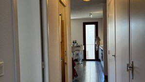 A narrow hallway with a ceiling light fixture, a door on the left, and a door on the right.