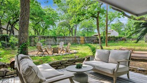 A covered outdoor patio with a sofa, chairs, and a round table. - Charming 3-bedroom Modern Rustic Retreat on 1 acre (Keller)