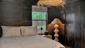A bedroom with a large bed, a window, a lamp, and a door. - Charming 3-bedroom Modern Rustic Retreat on 1 acre (Keller)