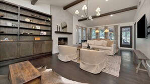 A spacious living room with a fireplace, a sofa set, and a wooden coffee table. - Charming 3-bedroom Modern Rustic Retreat on 1 acre (Keller)