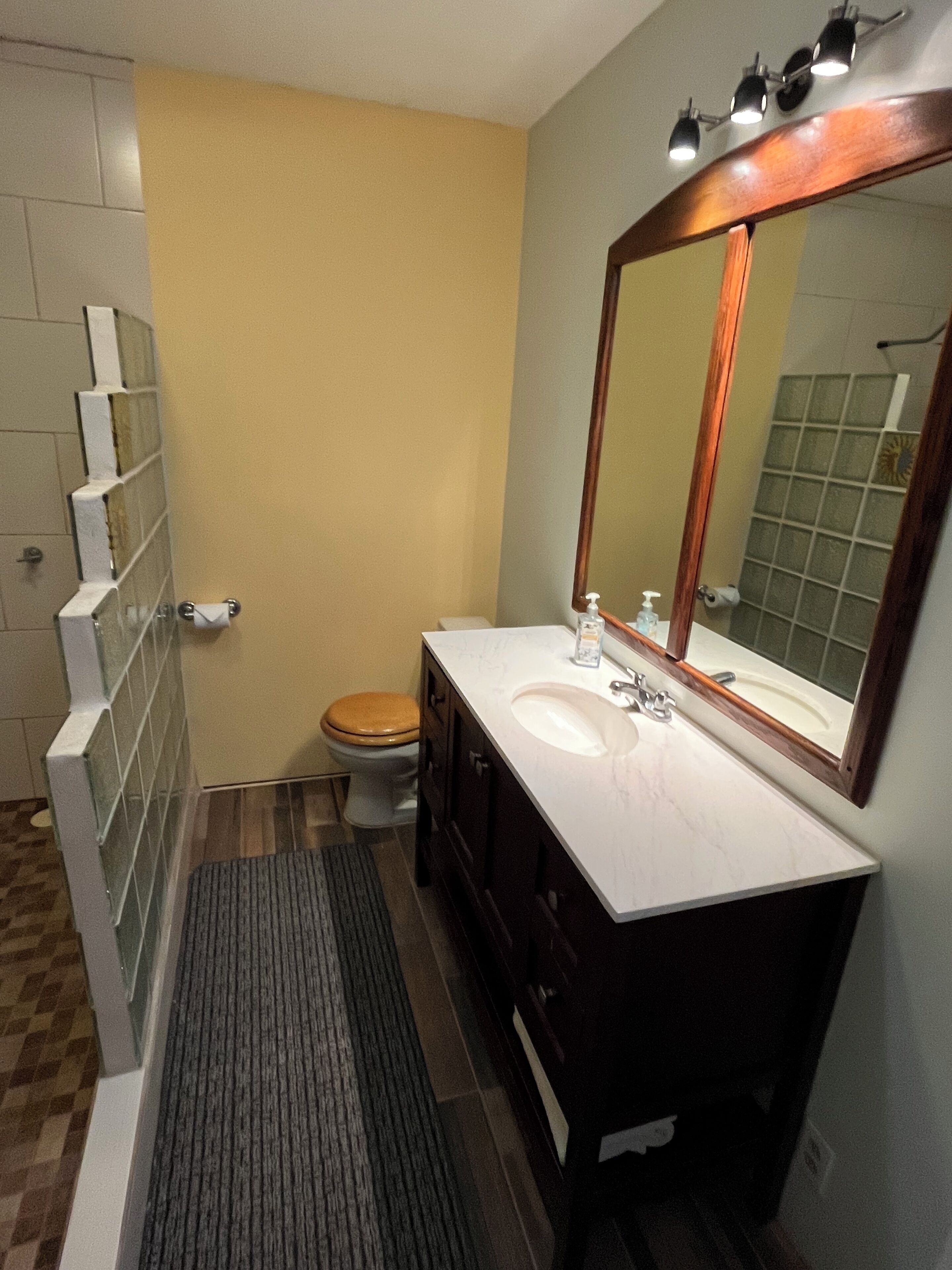Une salle de bain comprenant des toilettes, un lavabo, un miroir et un espace douche.
