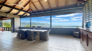 Enjoy a panoramic view of the coastline from this outdoor seating area with a table, chairs, and bar counter.