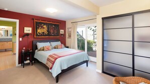 Un dormitorio con cama, mesitas de noche, un ventanal grande y una puerta corrediza.