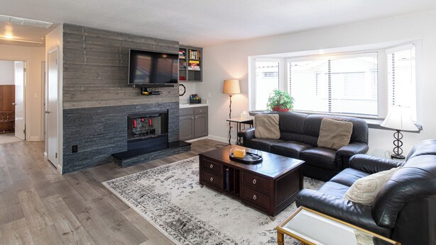 A living room with a fireplace, leather sofas, a coffee table, and a TV mounted on the wall. - 1277 Belridge Apt14C-Monthly (Oceano)