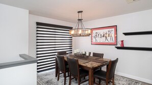A dining area with a wooden table, chairs, a chandelier, and a framed picture on the wall. - 1277 Belridge Apt14C-Monthly (Oceano)