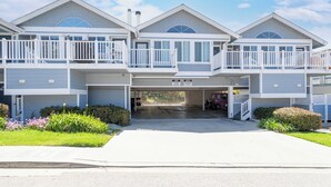 A two-story residential building with a central garage entrance, white railings on balconies, and a well-maintained front yard with flowers. - 364 Harbor View (Pismo Beach)