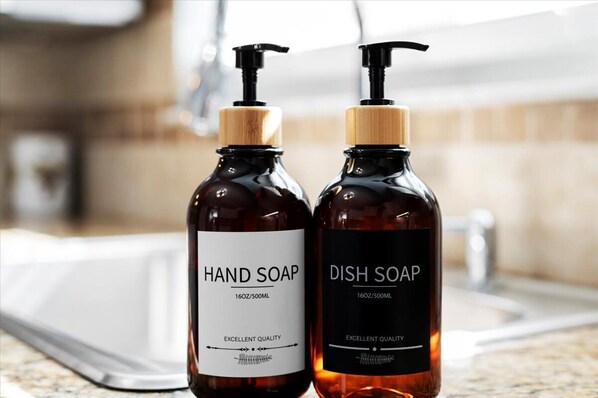 Two bottles of soap, one labeled 'HAND SOAP' and the other 'DISH SOAP', both with a pump dispenser and a wooden cap.