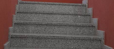 A staircase with granite steps, white walls, and a red accent wall.