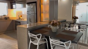 A modern kitchen with a central island, white chairs, and a dining table.