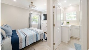 Een slaapkamer met een bed, een kast en een badkamer met een wastafel en spiegel.