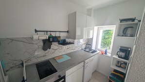 A compact kitchen with a built-in oven, a sink, and a window providing natural light. - Small city apartment Remscheid (Remscheid)