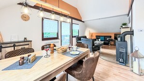 A modern kitchen with a wooden table, chairs, and a hanging light fixture.