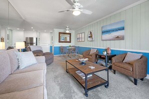 A living room with a sofa, armchairs, a coffee table, and a dining area with chairs and a table.
