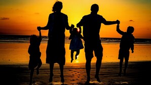 A silhouette of a family against a sunset on a beach.