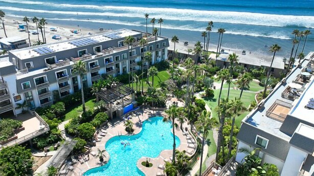 A hotel with a rooftop pool, a beach view, and a landscaped garden.