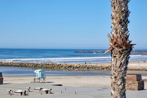 Una torre de salvavidas, una palmera y una costa rocosa con olas.