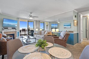 A spacious living room with a fireplace, comfortable seating, and a view of the ocean.
