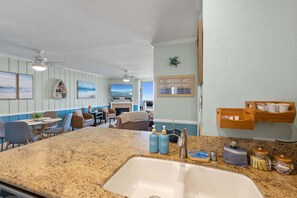 Una cocina con encimera de granito, un fregadero y un mueble de madera con frascos.