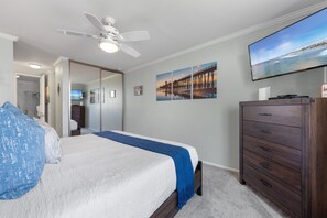 Ein Schlafzimmer mit einem Bett, einem Schminktisch, einem Fernseher und einem Deckenventilator.