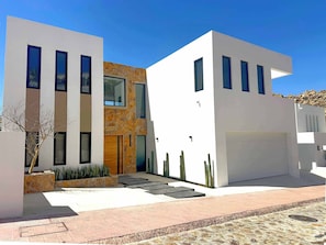 Um edifício moderno de dois andares com fachada de pedra, grandes janelas e telhado plano.
