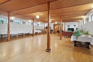 Un grand hall doté d’un plancher en bois, d’un plafond en briques et de murs blancs.