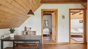 A room with a wooden ceiling, a dining table with benches, a potted plant, and a bed with a white duvet. - Margretehøj Manor in scenic surroundings (Grenaa)