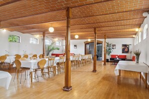Ein großzügiger Essbereich mit Holzboden, weißen Tischen und Stühlen.