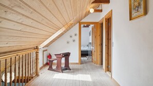A wooden interior with a sloped ceiling, a staircase, and a bed in the background. - Margretehøj Manor in scenic surroundings (Grenaa)