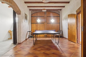 Quarto com mesa de pingue-pongue, uma cadeira, um abajur e porta com painéis de madeira.