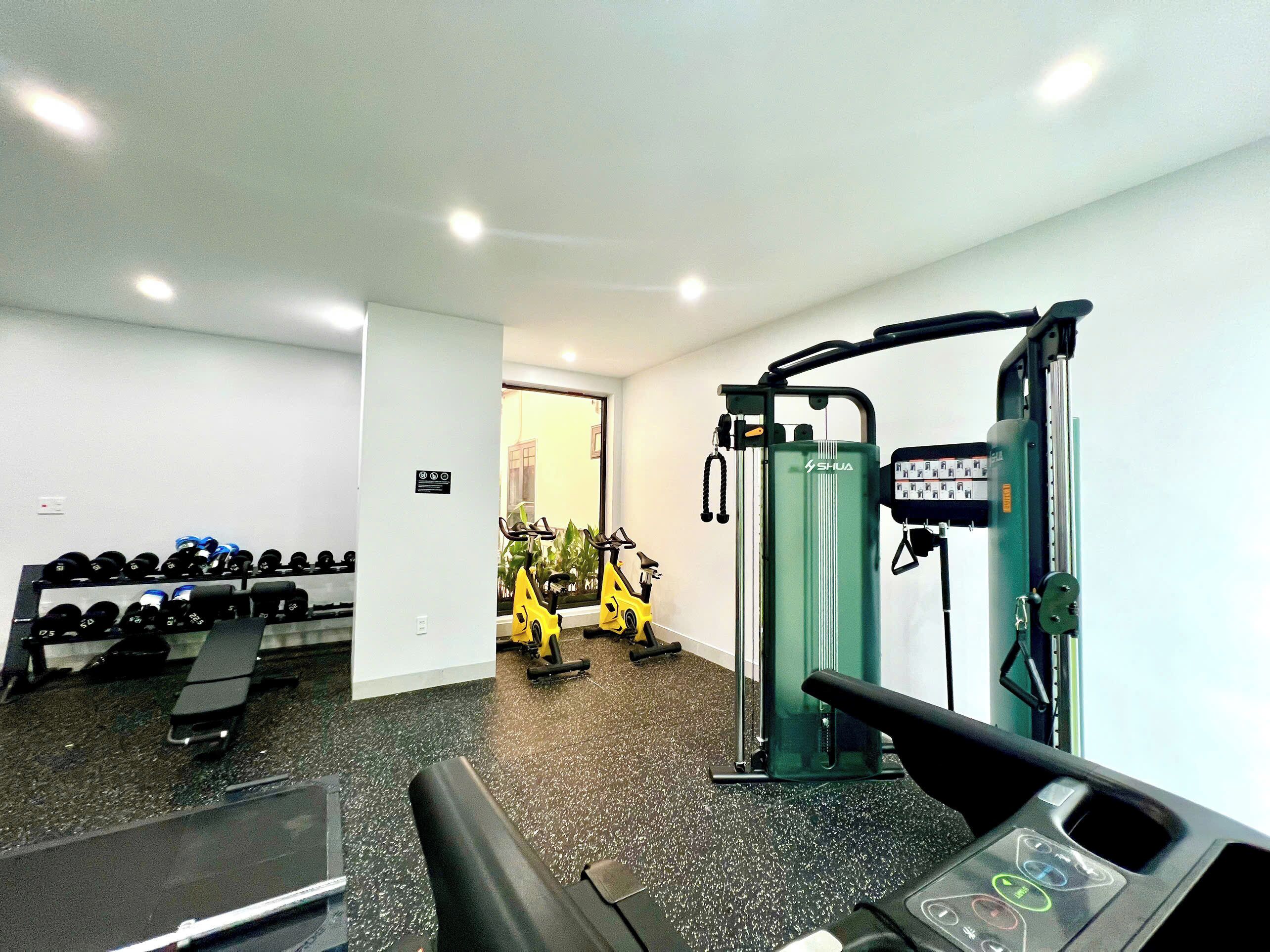 Un gimnasio con equipo de ejercicio, una banca y mancuernas.