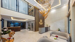 A modern hotel lobby with a reception desk, seating area, and a chandelier. - Cat Ba Wistaria Hotel - Pool & Massage (Hai Phong)