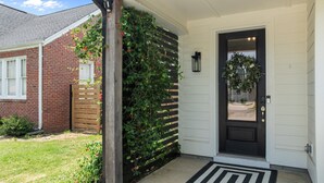 A house with a black front door, a wooden gate, and a brick wall.