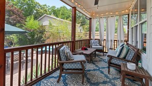 A covered patio with wooden furniture, string lights, and a ceiling fan.