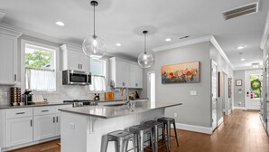 A modern kitchen with white cabinetry, stainless steel appliances, and a central island with bar stools.
