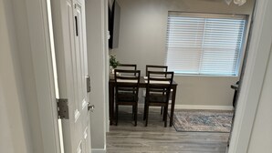 A hallway with a welcome mat, a dining area with two chairs and a table, and a window with blinds. - New apartment on Main Street in Mackay (Mackay)