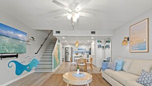 A modern living room with a staircase, a dining area, and a kitchen.