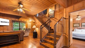Un interior de madera con una escalera, un sofá, una lámpara y un letrero que dice 'VACATIONSTAR'.