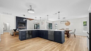 Une cuisine moderne avec des meubles de couleur sombre, un îlot central et des luminaires suspendus.