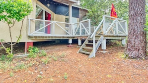 Eine rustikale Holzhütte mit einer Holzterrasse und einer kleinen Treppe, die zu einer roten Tür führt.