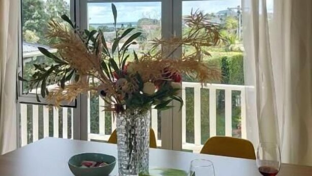Une table à manger ornée d’un vase de fleurs, d’un bol et d’un verre à vin.