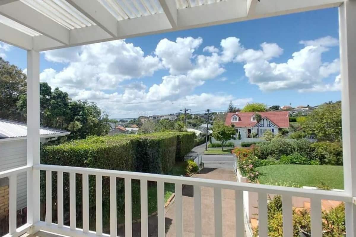 A balcony with a view of a residential area, including houses and greenery.