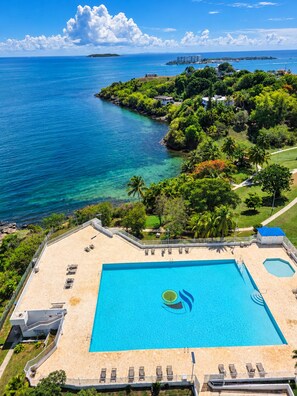 A resort with a large swimming pool, a beach area, and a view of the ocean.