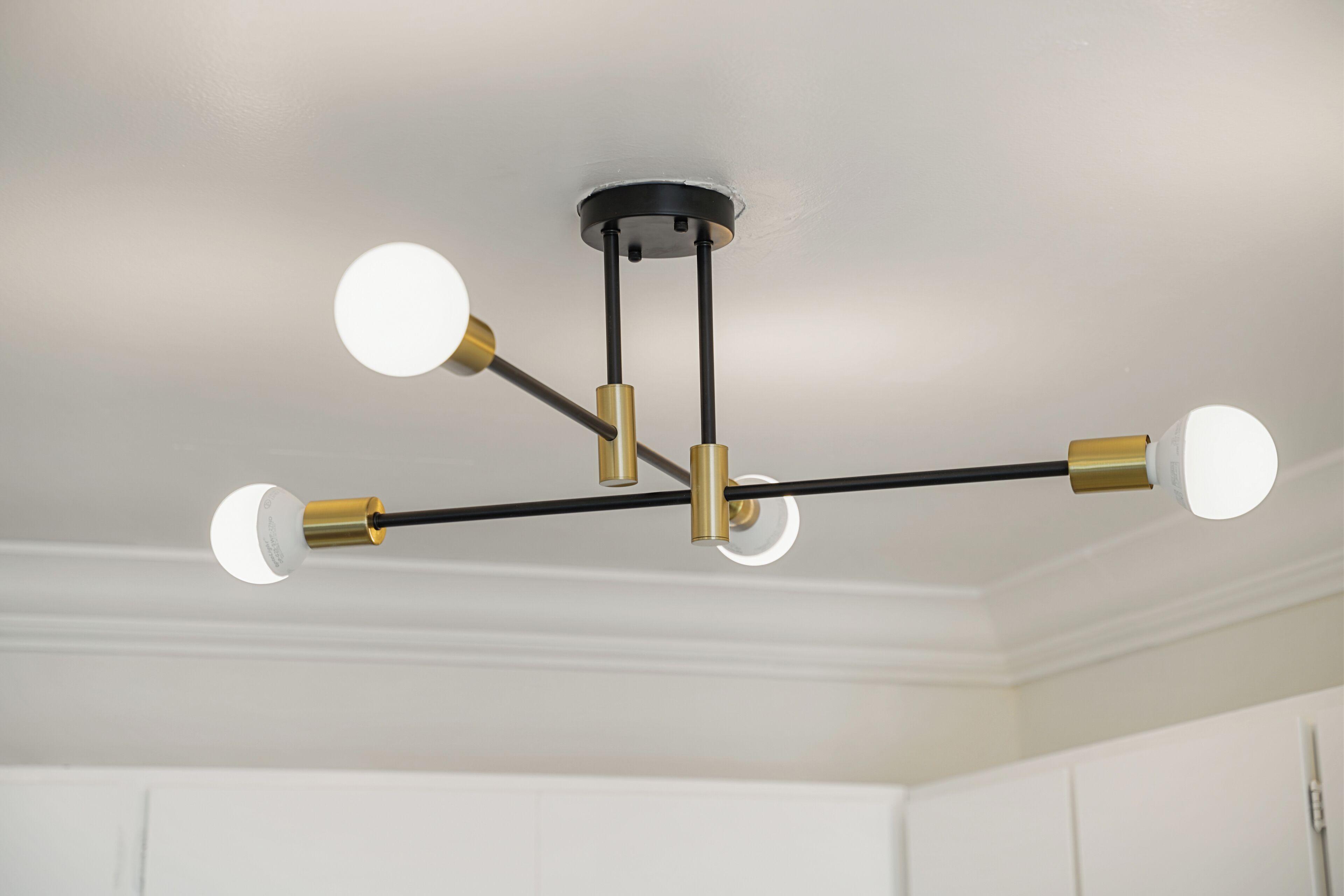 A ceiling with a black and brass chandelier with four lights.