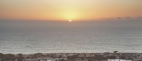 A coastal town at sunset with a view of the sea and residential buildings.