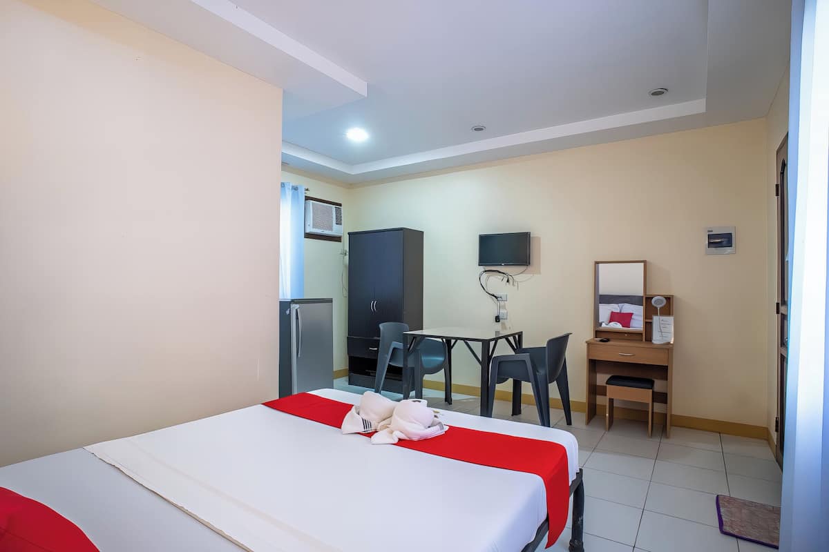 Une chambre d’hôtel équipée d’un lit, d’un bureau, d’une chaise, d’une télévision et d’une armoire.