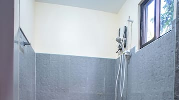 Un baño pequeño con un inodoro, un cubo rojo y una ducha.