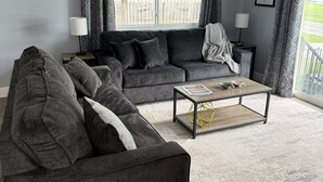 A living room with a grey sofa, a coffee table, and a view of a balcony.
