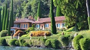 A large, multi-story building with a terraced garden and a body of water in the foreground. - VILLA RELAX - Alta Brianza (Veduggio Con Colzano)