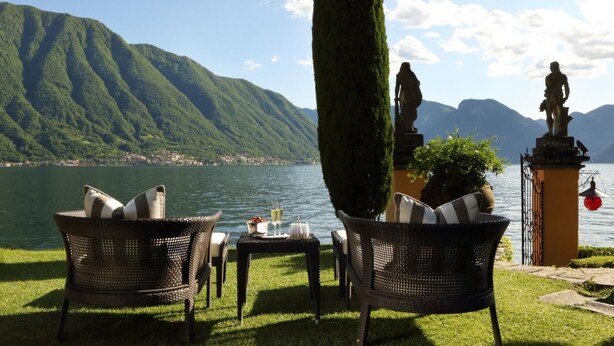 A lakeside terrace with wicker chairs, a table with glasses, and a statue. - VILLA RELAX - Alta Brianza (Veduggio Con Colzano)