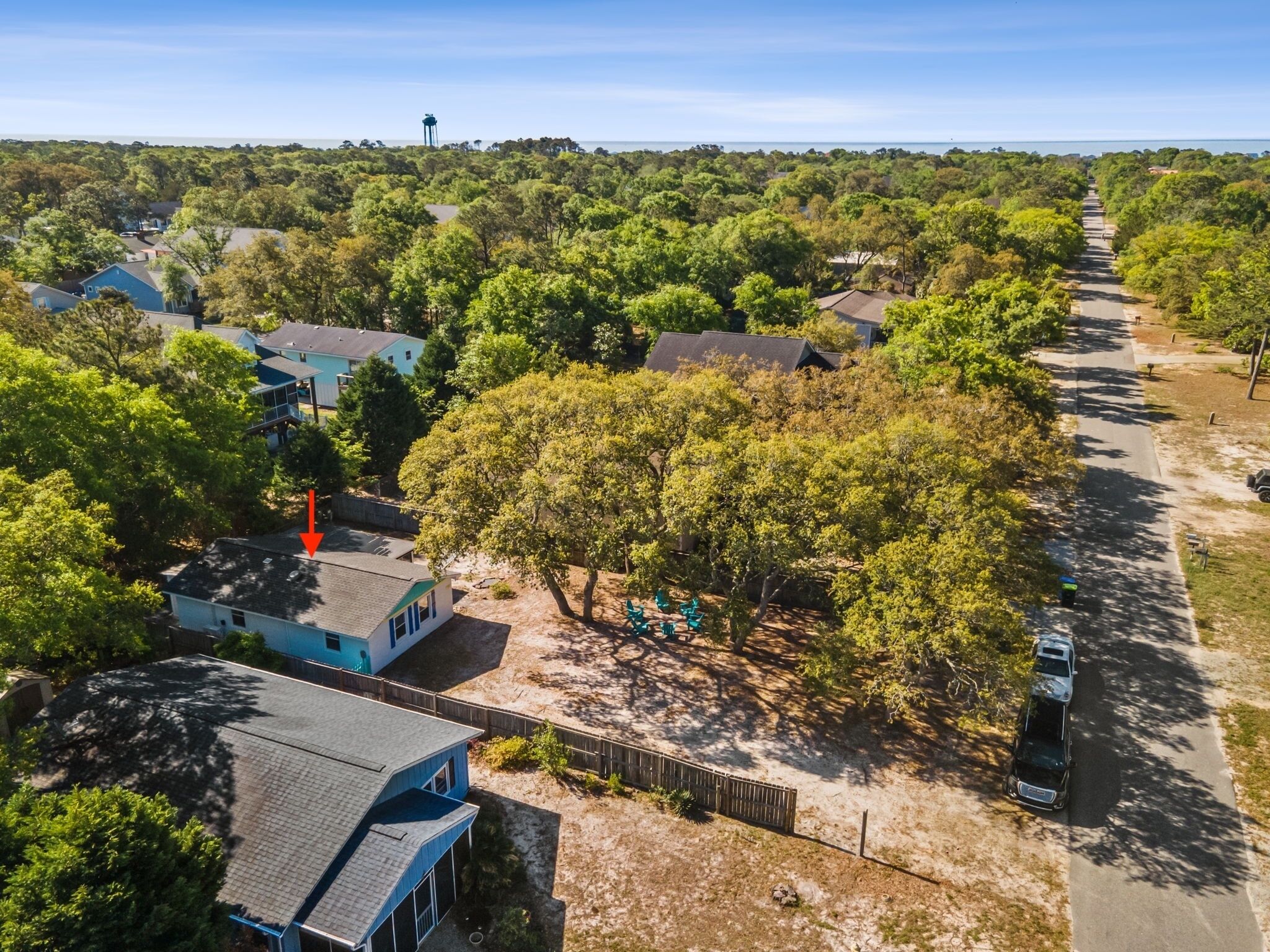 An aerial view of a residential area with houses, a large tree, and a road.